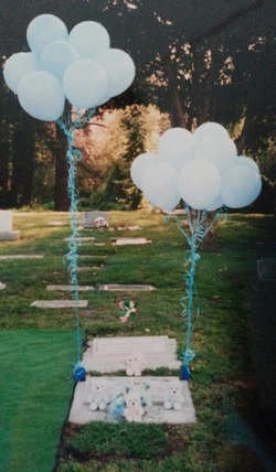 child's gravesite with teddybears and blue balloons